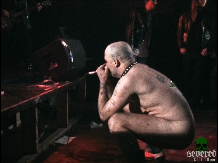 Naked GG Allin squatting on stage.