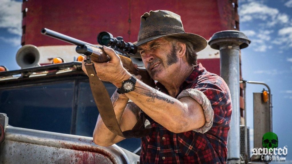 Photo of John Jarret as Mick Taylor in Wolf Creek 3 holding a rifle.